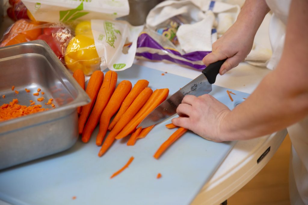 A set of hands chopping carrots