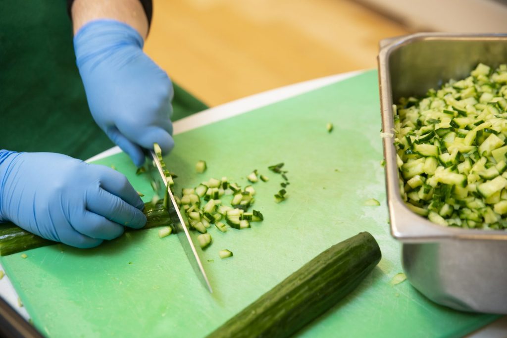 A set of hands chopping cucumbers