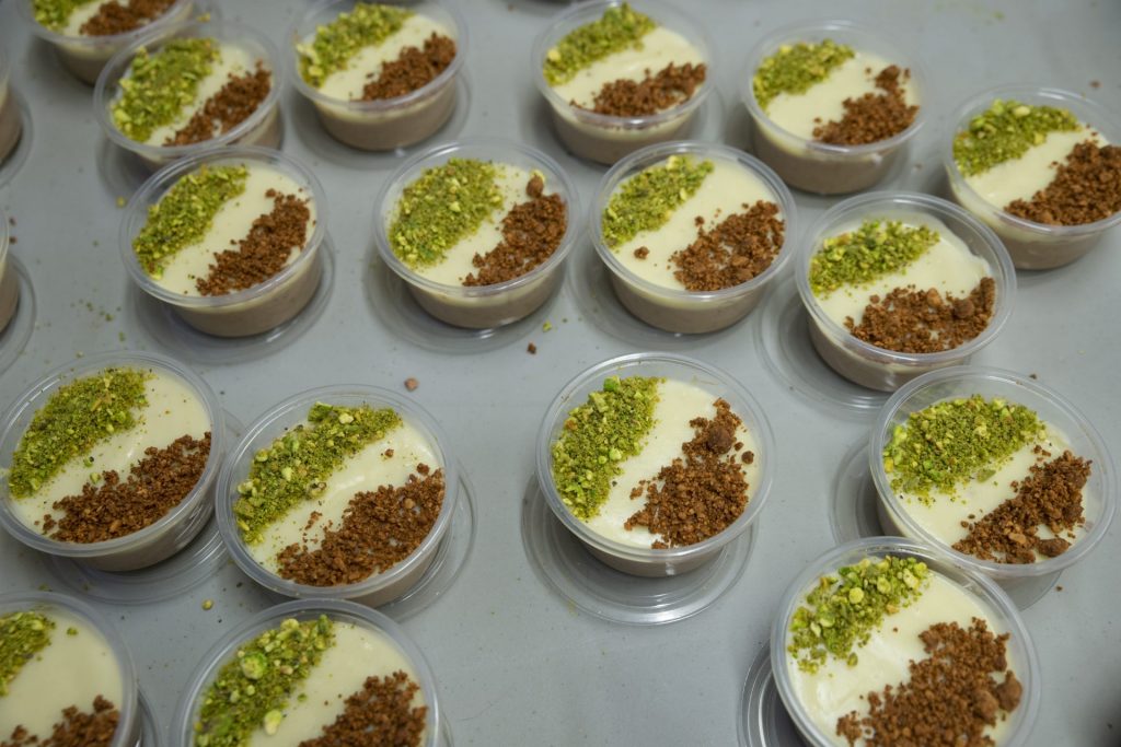 Multiple small containers of assida, topped with green and brown ground nuts