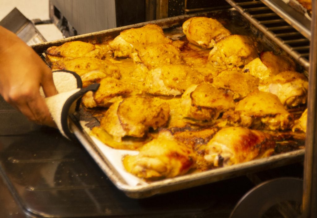 Roasted chicken being taken from an oven