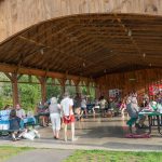 A pavilion with people on picnic tables and a band playing