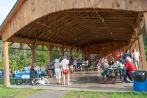 A pavilion with people on picnic tables and a band playing