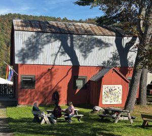 People at a picnic table by a red barn. Image: A. Zelie