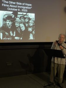 Discussion host standing in front of movie screen. Image: K. McCracken.